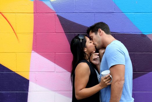 A in love couple kissing in front of a wall.