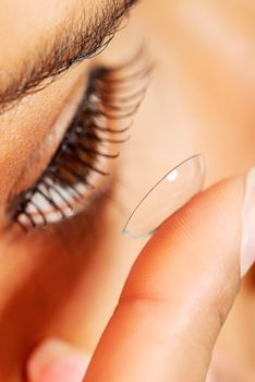 Woman putting contact lens in her eye 