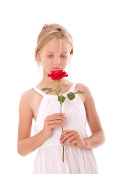 young girl in white dress smelling a rose