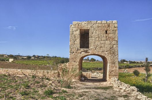 An elevated birthing chamber in the Maltese countryside, with an underlying arched underpass.