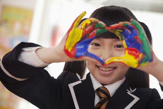 Smiling schoolgirl finger painting, close up on hands 