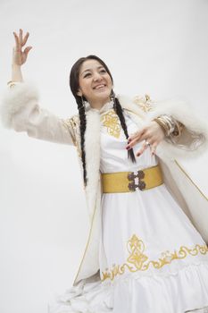 Portrait of young dancing woman with braids in traditional clothing from Kazakhstan, studio shot