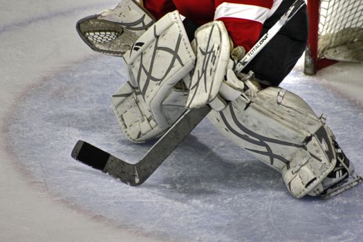 View of hockey goaltender pads and stick in defensive position