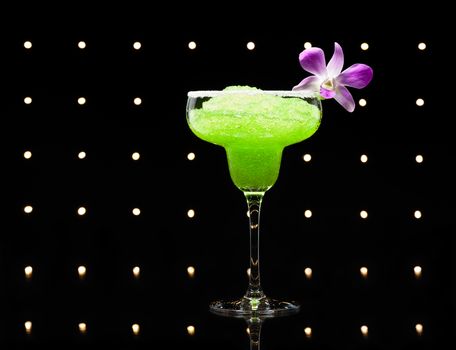 Green margarita cocktail in front of disco lights