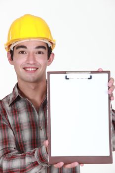 Young construction worker holding up a blank clipboard