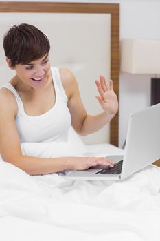 Woman using video chat on laptop in bed