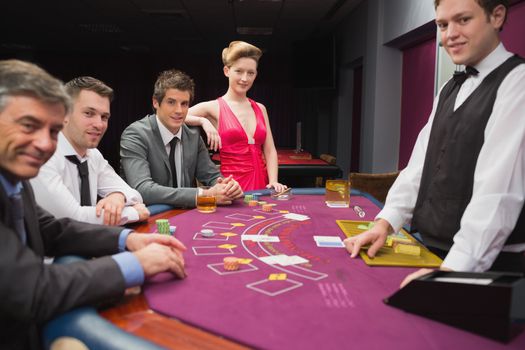 People sitting at blackjack table and smiling