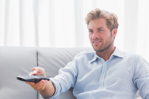 Man changing tv channel sat on the couch