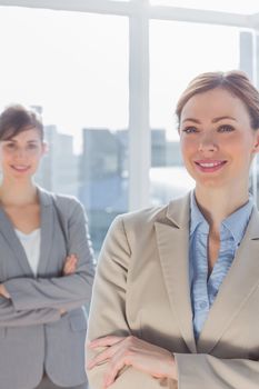 Happy businesswomen with arms crossed smiling at camera