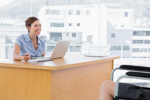 Businesswoman smiling at disabled interviewee