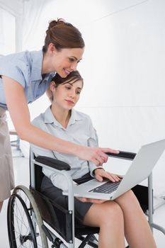 Disabled businesswoman looking at laptop with colleague