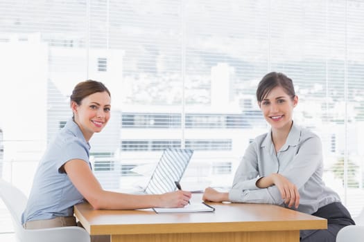 Businesswomen having a meeting at desk and smiling at camera