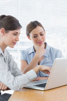 Two businesswomen working on laptop together