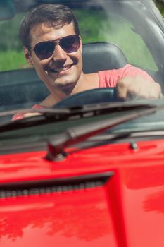 Cheerful handsome man driving his cabriolet