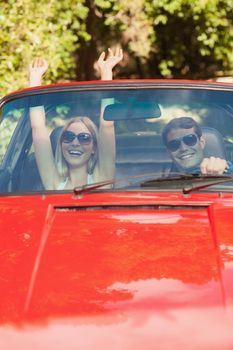 Loving couple having fun in their red cabriolet