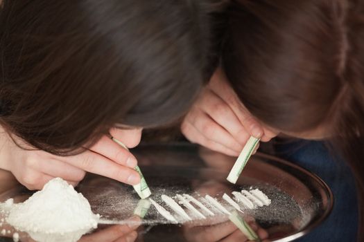 Two girls snorting an illegal white powder