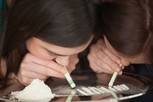 Two young girls snorting an illegal white powder