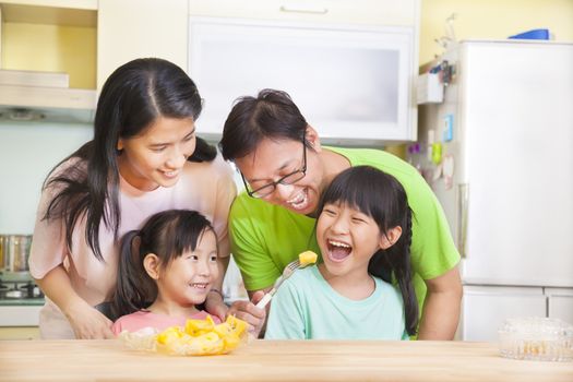 happy family and daughter eating fruits in the kitchen