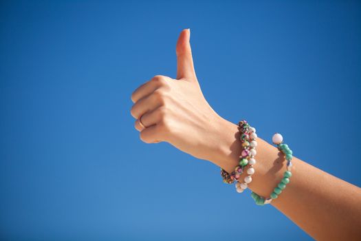 Thumbs up sign on a woman's hand against the turquoise sea