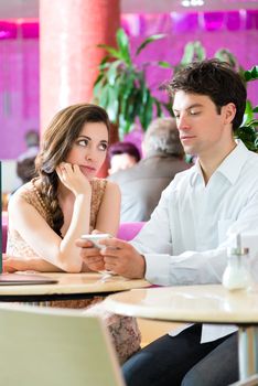 Young couple in cafe not interacting but on phone