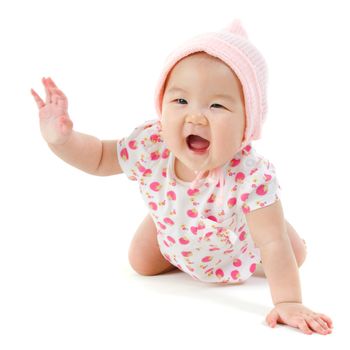 Six months old Asian baby girl crawling over white background, isolated.
