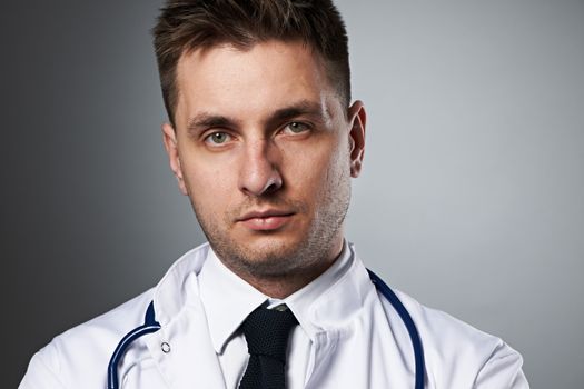 Medical doctor with stethoscope portrait against grey background 