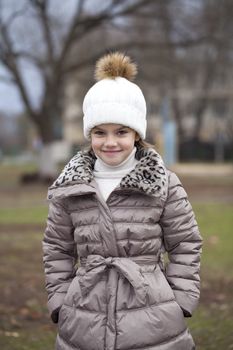 Little girl in a white knitted hat autumn