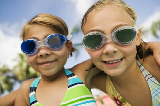 Closeup portrait of two smiling girls wearing swim goggles