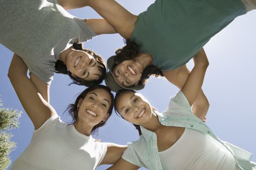 View from below portrait of four women in huddle against clear sky