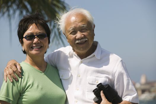 Senior couple with binoculars outdoors (portrait)