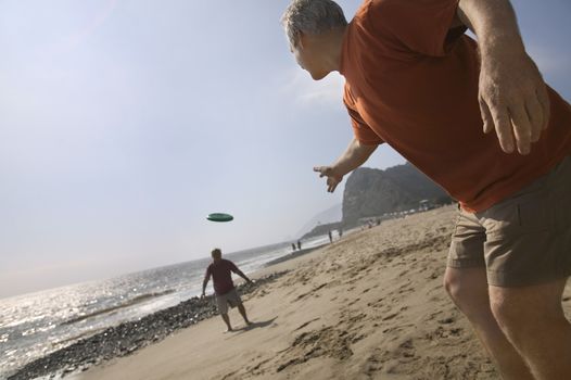 Two men playing with flying disc on beach