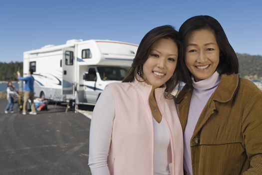 Mother and teenage daughter standing outside of RV at lake