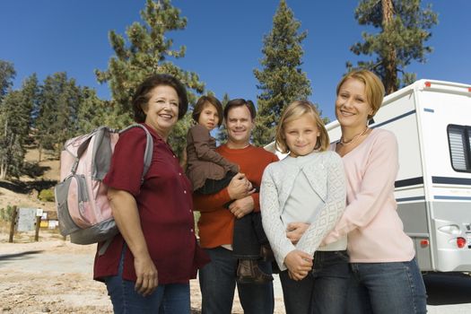 Three-generation family standing outside of RV in campground