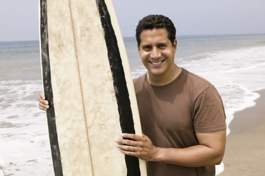 Portrait of man holding surfboard on beach