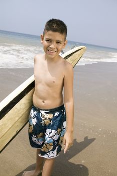 Portrait of boy holding surfboard on beach