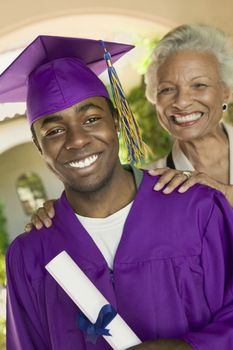 Portrait of a male graduate with his happy grandmother standing outside