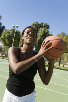 Happy African American woman with basket ball in court