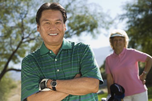Portrait of a male golfer with woman standing in background