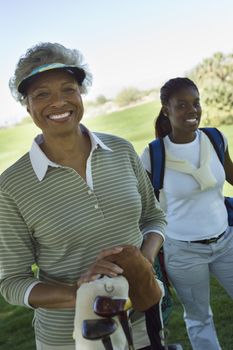 Portrait of happy African American female golfer with person in background