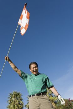 Excited male golfer holding flag after a winning game