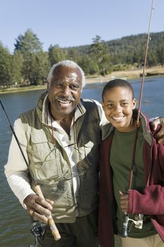 Portrait of happy senior man with grandson fishing on a sunny day