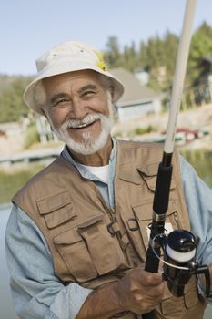 Portrait of happy Hispanic senior man fishing