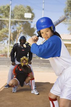 Portrait of an Asian baseball player ready for a shot with competitor and referee in background