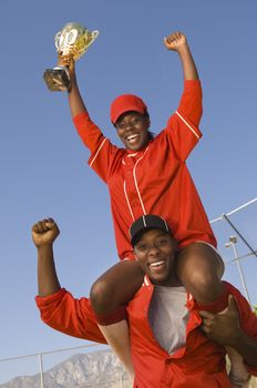 Portrait of cheerful African American baseball players with trophy