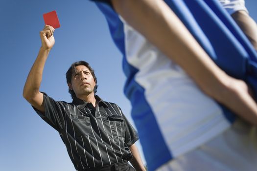 Low angle view of referee indicating red card dismissal to player