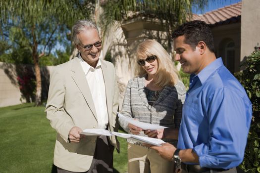 Happy couple with real estate agent discussing paperwork