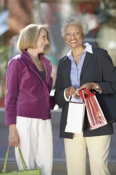 Portrait of happy African American woman with shopping bags standing with a friend