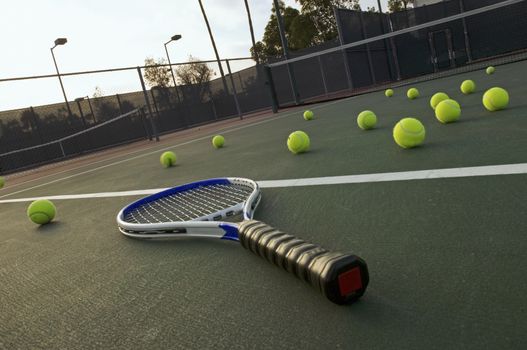 Tennis balls and racquet on empty tennis court