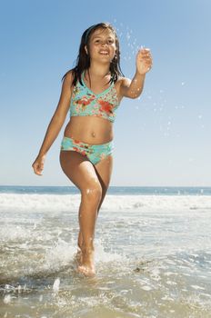 Full length of a teenage girl in swimwear running on beach