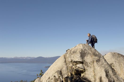 Side view of male hiker on boulder at coast